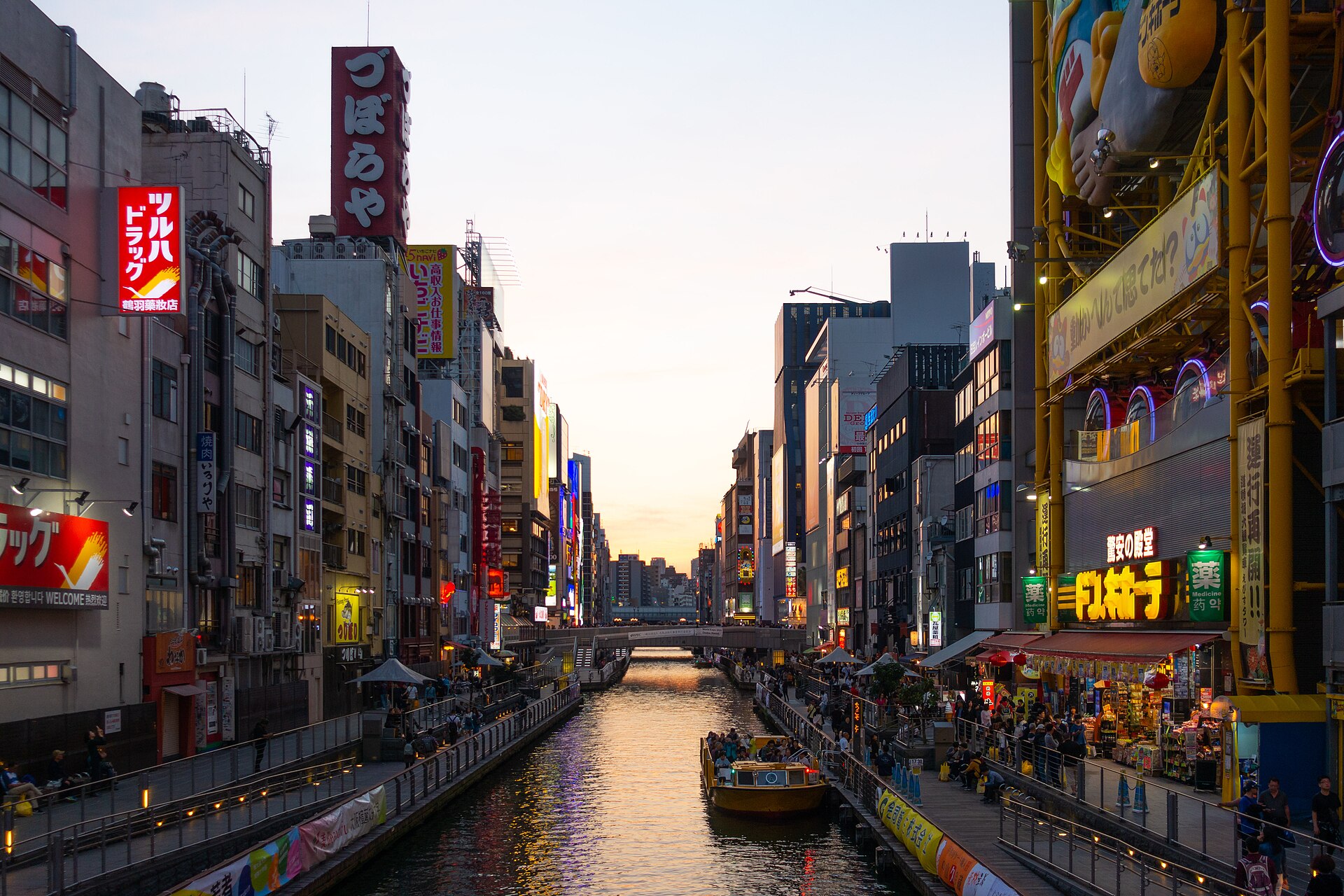 El canal de Dōtonbori y sus letreros al atardecer, con un barco turístico